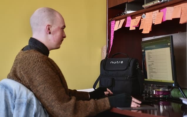 Bald man working at desk with sticky notes and Nutre bag.